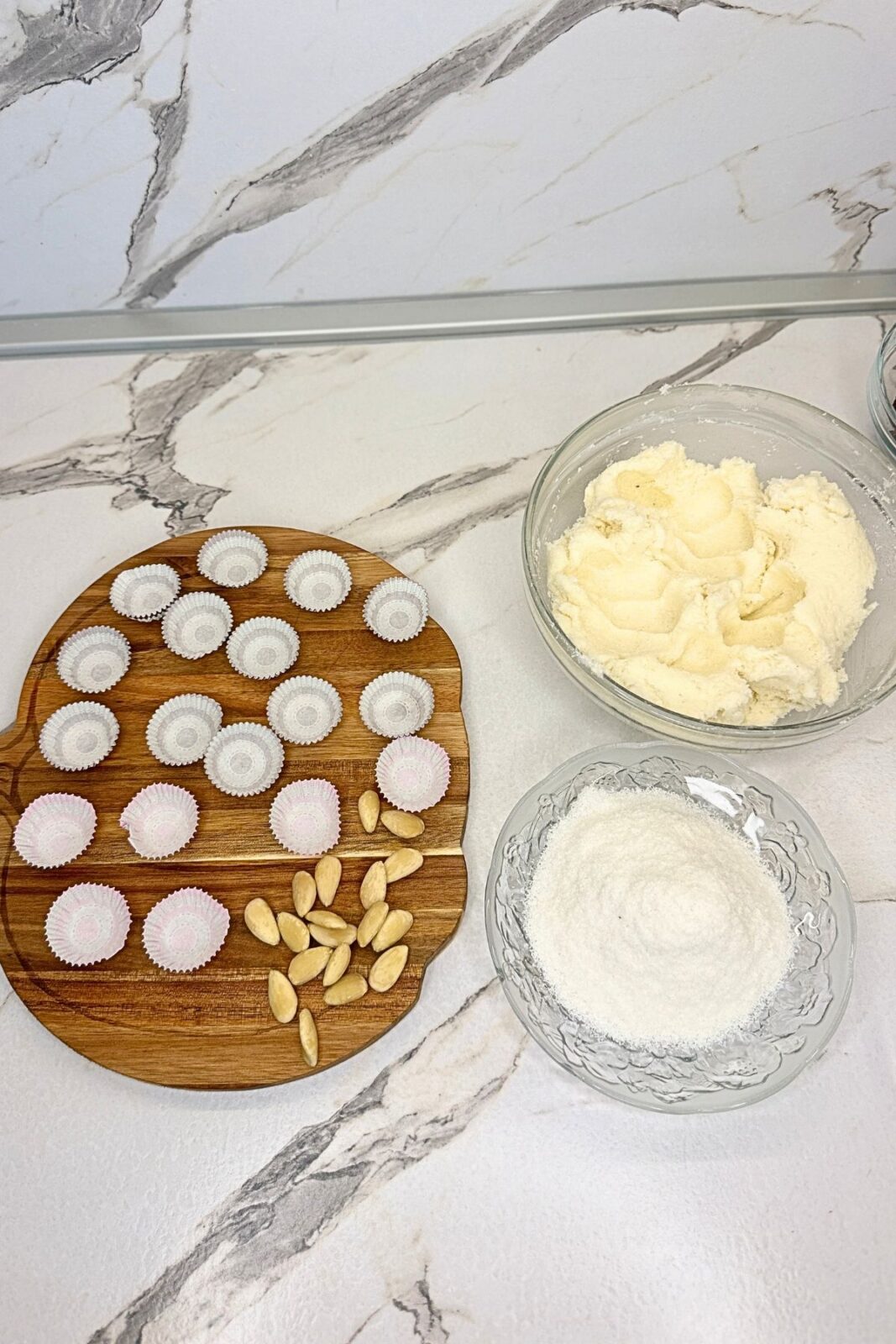 A whole blanched almond placed in the center of flattened coconut filling before shaping into a ball.