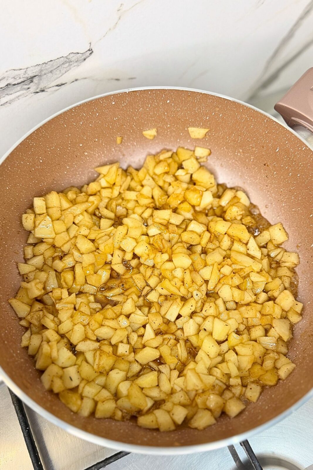 Diced apples cooking in a cinnamon brown sugar sauce for apple pie cookies.