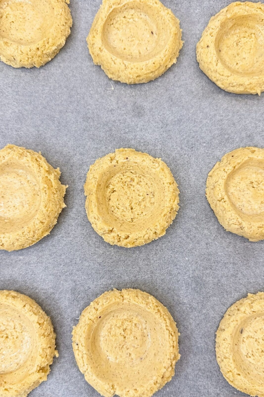 Unbaked cinnamon cookies with center indentations ready for apple filling.
