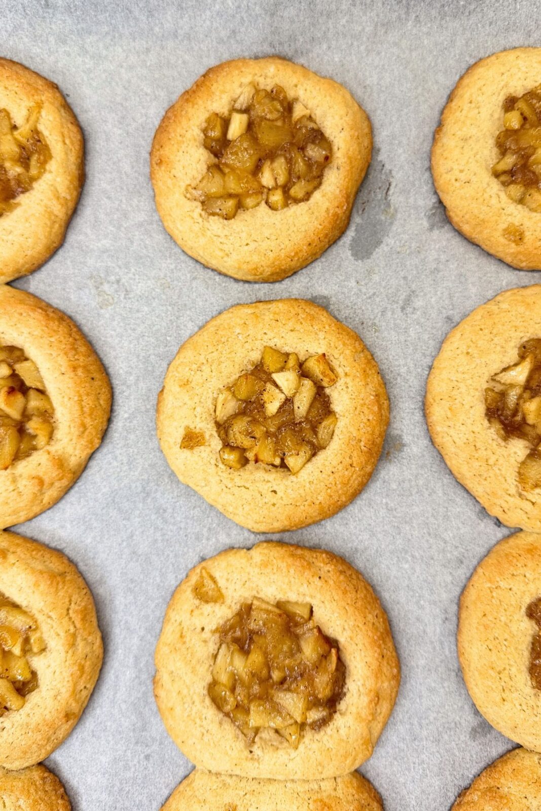 Freshly baked apple pie cookies with golden edges and cinnamon apple centers.