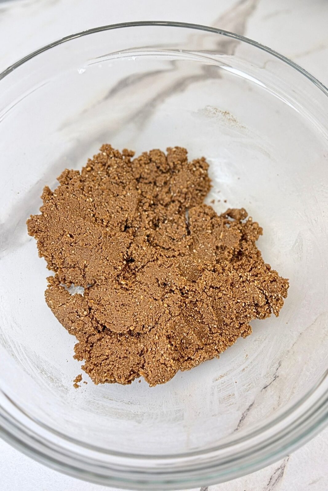 Cocoa cookie dough mixed until evenly combined in a glass bowl for chocolate coconut roll.
