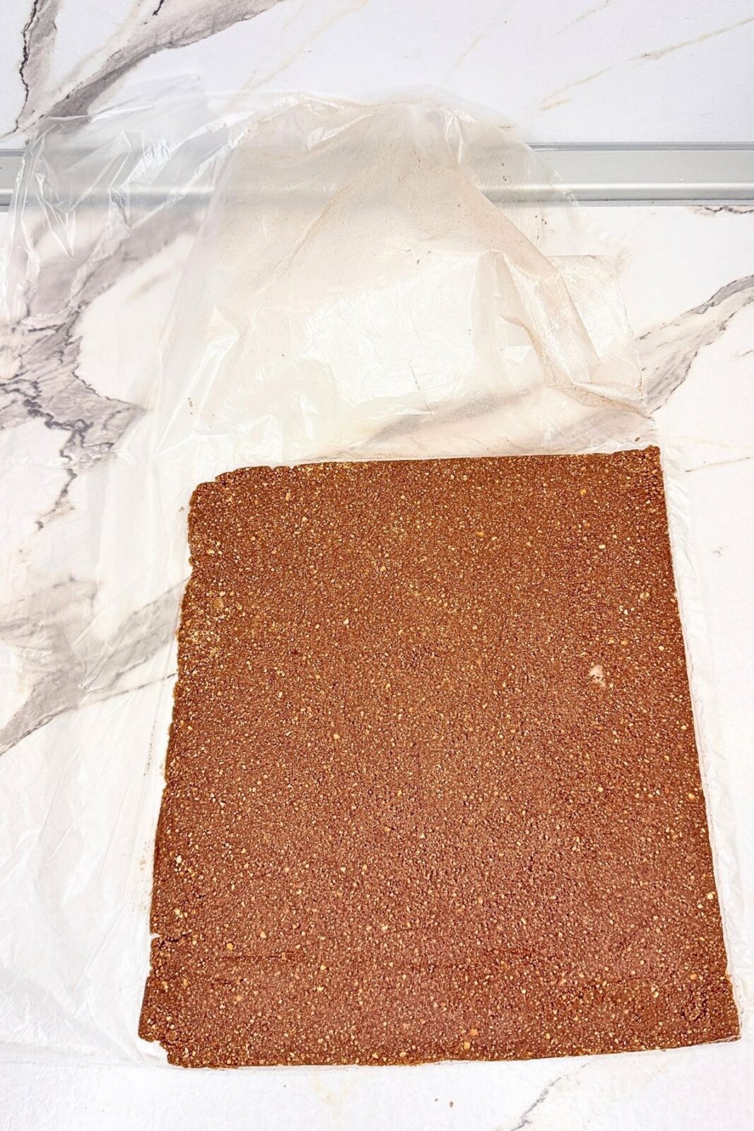 Rectangular cocoa cookie layer exposed after opening the freezer bag, ready for the coconut filling.