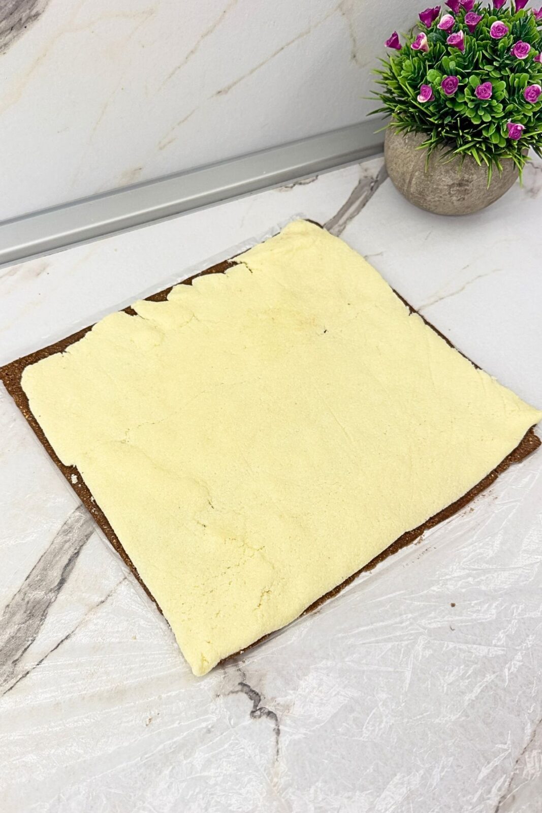 Rectangular coconut filling placed over the cocoa cookie layer before rolling into a log.