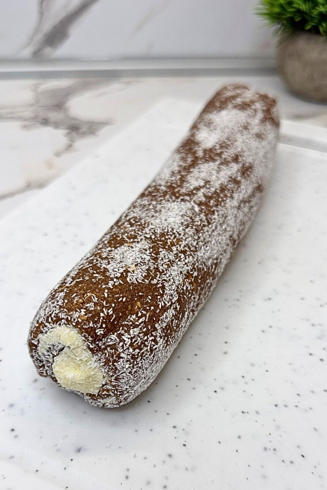 Chilled chocolate coconut roll with slices arranged around it, showing the cocoa cookie and coconut filling spirals.