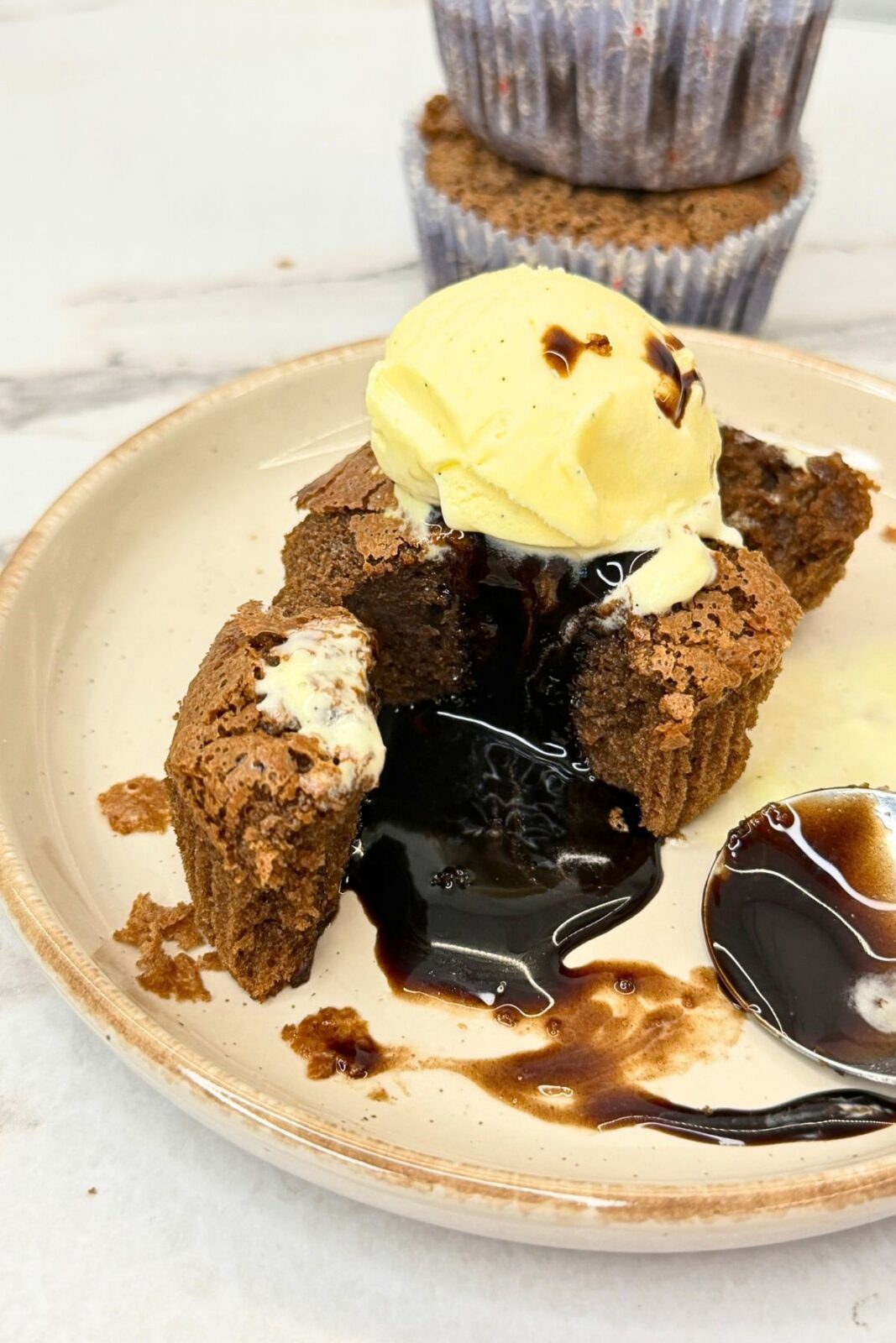 Warm chocolate lava cake broken open to reveal its molten center, topped with vanilla ice cream.