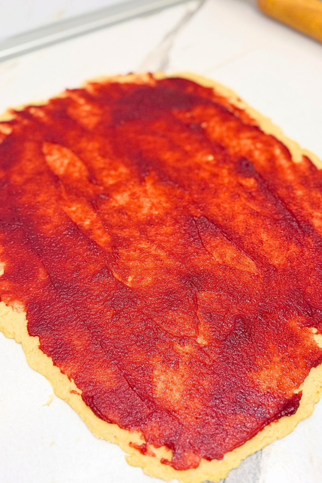 Rolled-out cranberry bread dough spread with an even layer of cranberry jam.