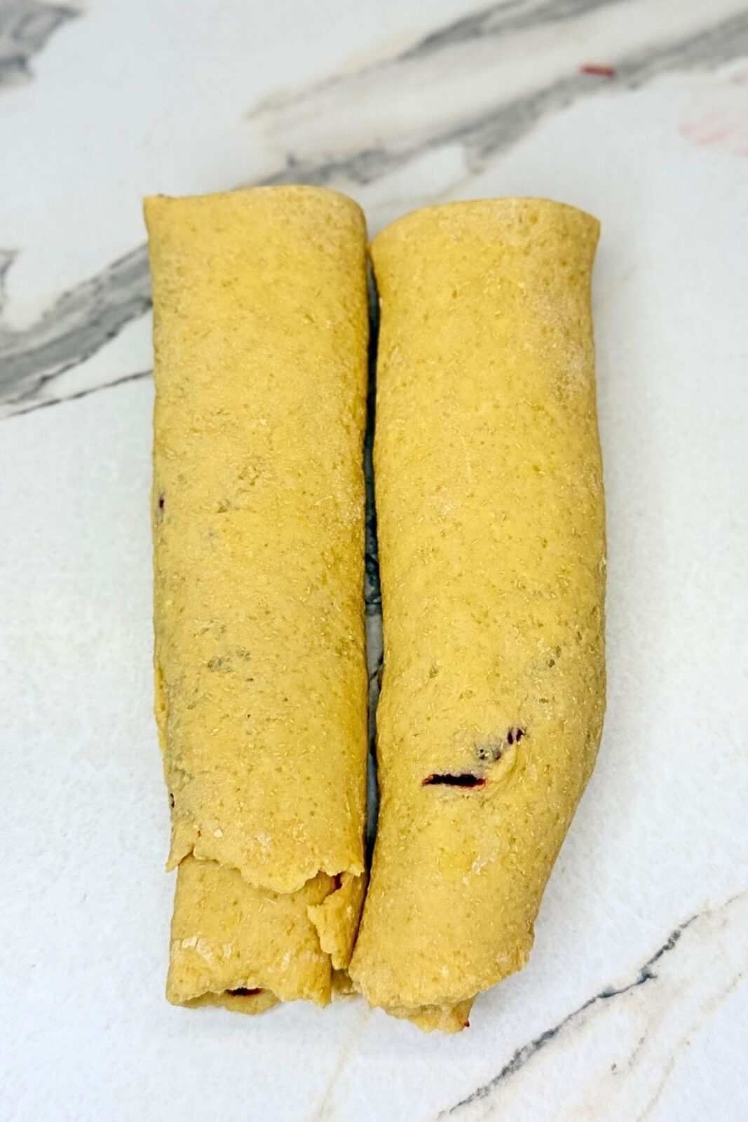 Cranberry jam-filled dough divided into two long pieces before braiding.