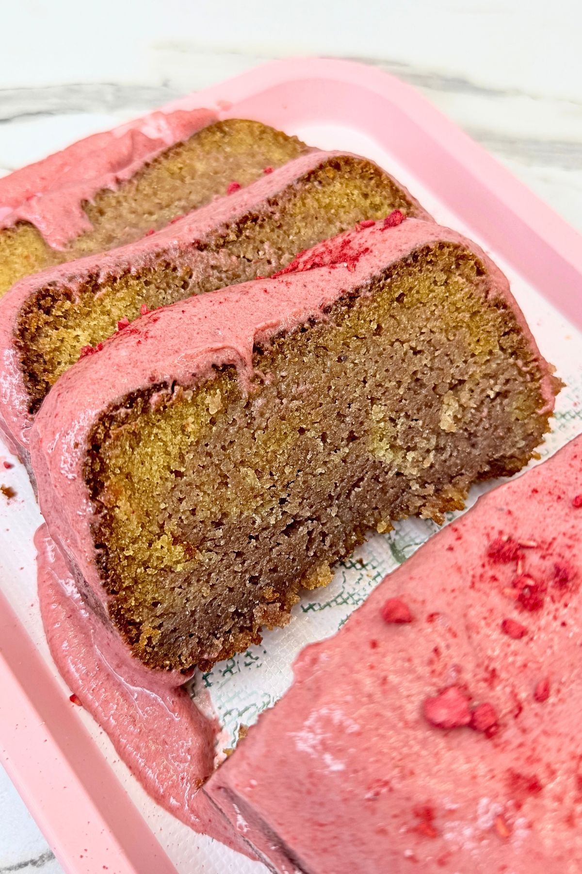 Cranberry loaf cake with cranberry cream cheese glaze, sliced to show the marbled crumb on a white serving platter.