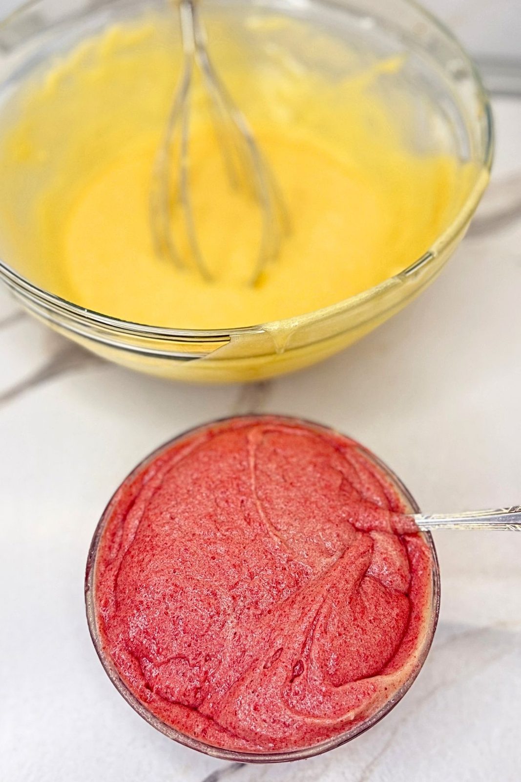 Pink cranberry jam batter in a small bowl beside the plain vanilla batter.