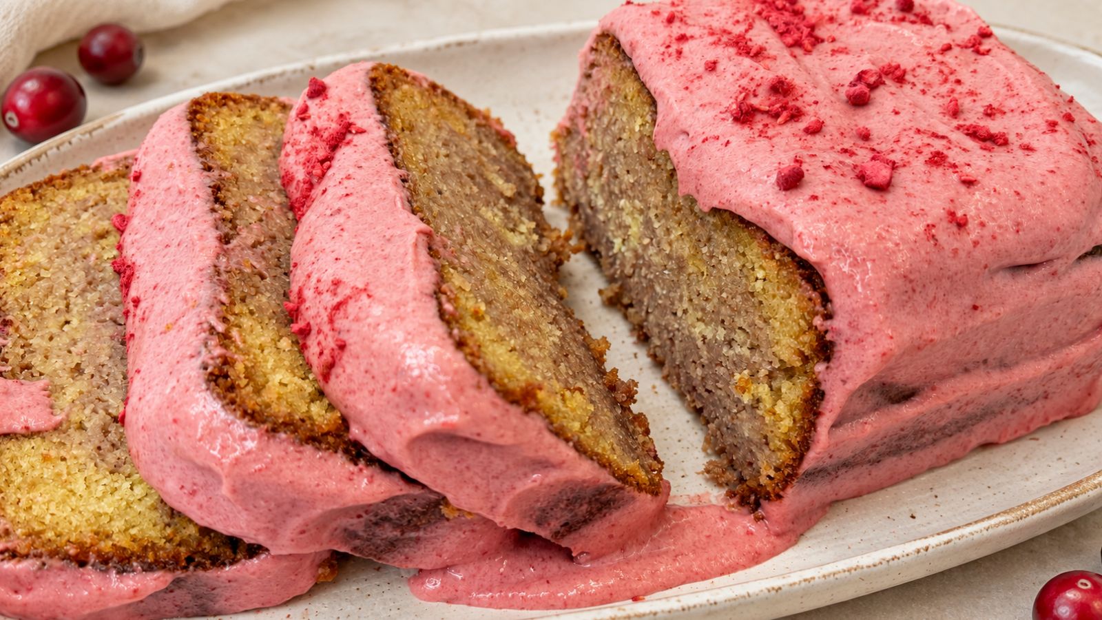 Cranberry loaf cake with cranberry cream cheese glaze, sliced to show the marbled crumb on a white serving platter.