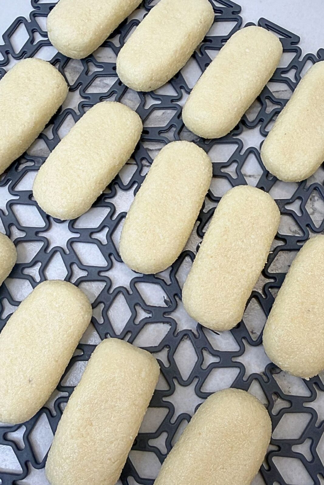 Coconut filling shaped into small rectangular bars with rounded ends on a patterned tray.