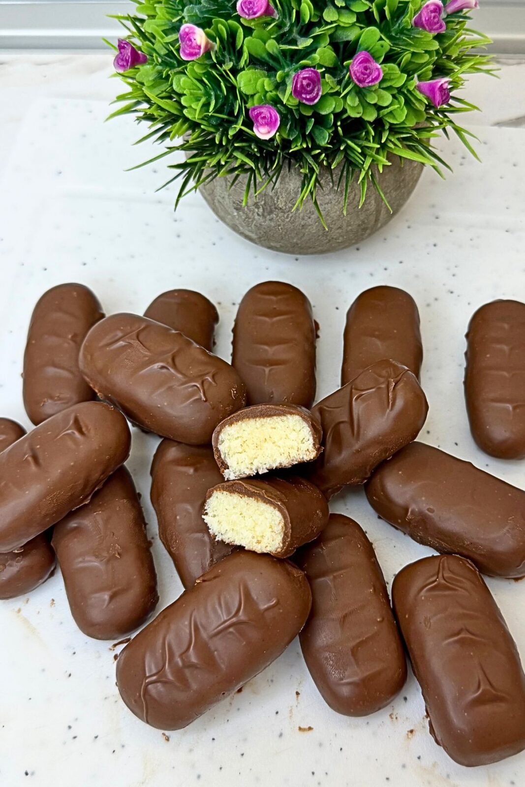 Freshly dipped homemade bounty bars resting on a wire rack while the milk chocolate coating sets.