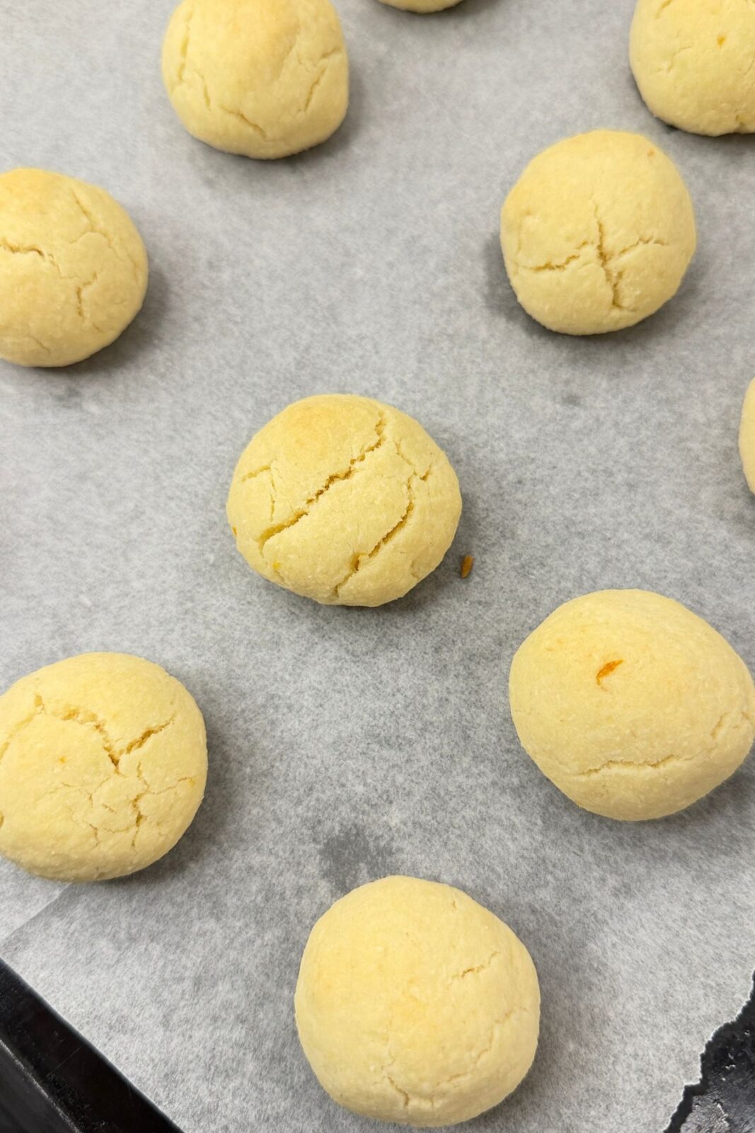 Freshly baked lemon coconut shortbread cookies cooling on a parchment-lined baking sheet.