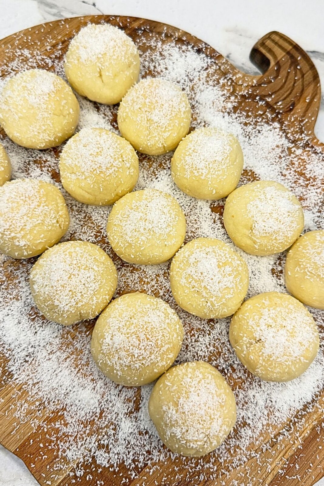 Glazed lemon coconut shortbread cookies sprinkled with coconut and resting on a wire rack.