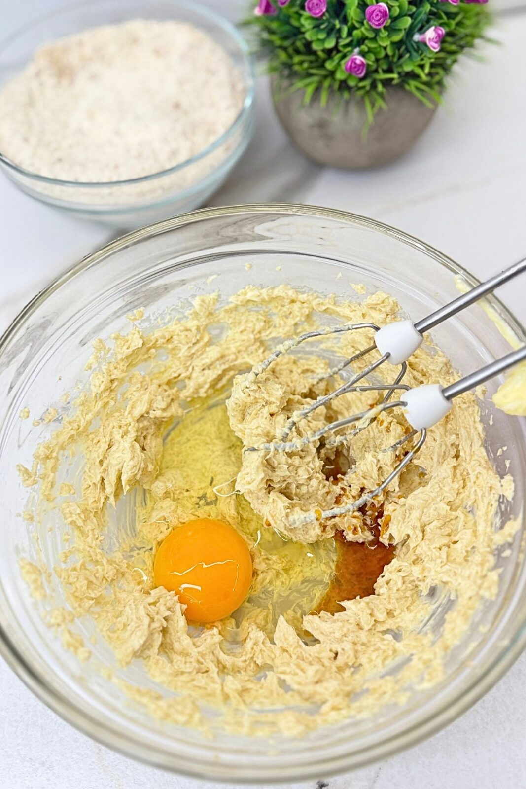 Egg and vanilla extract added to creamed butter and brown sugar for Linzer cookies.