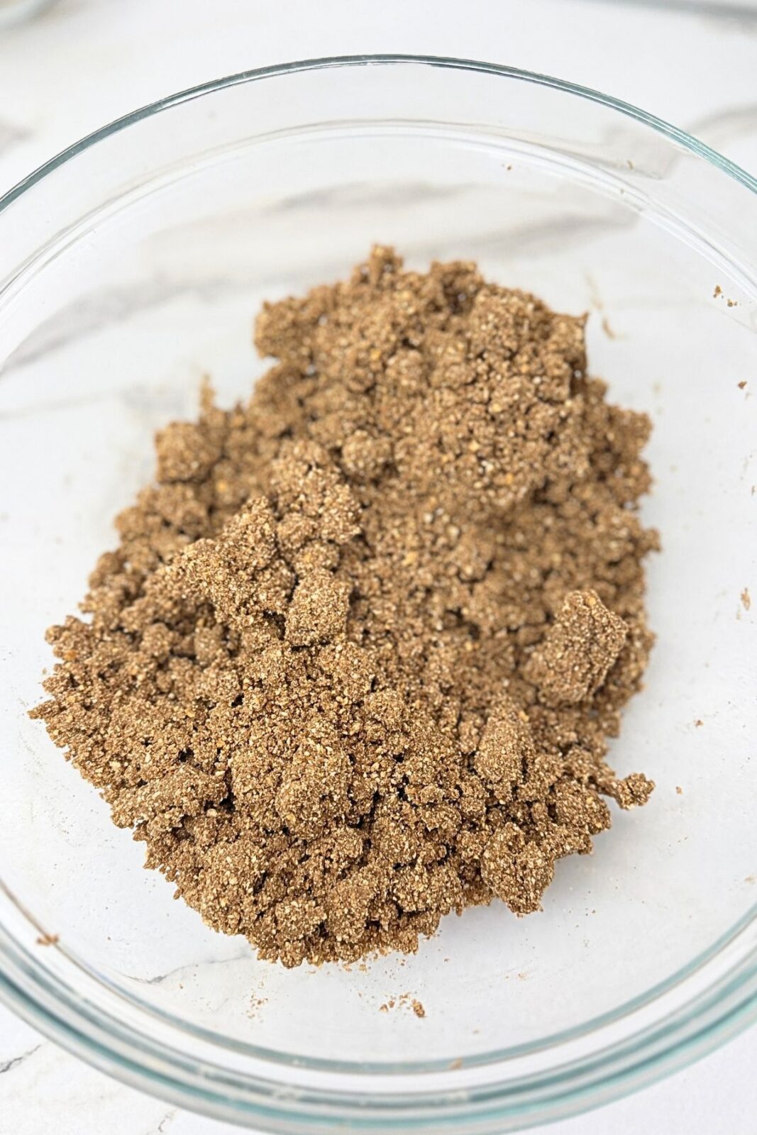 Cocoa cookie crumbs mixed with milk in a glass bowl for the no-bake Ferrero Rocher cake crust.