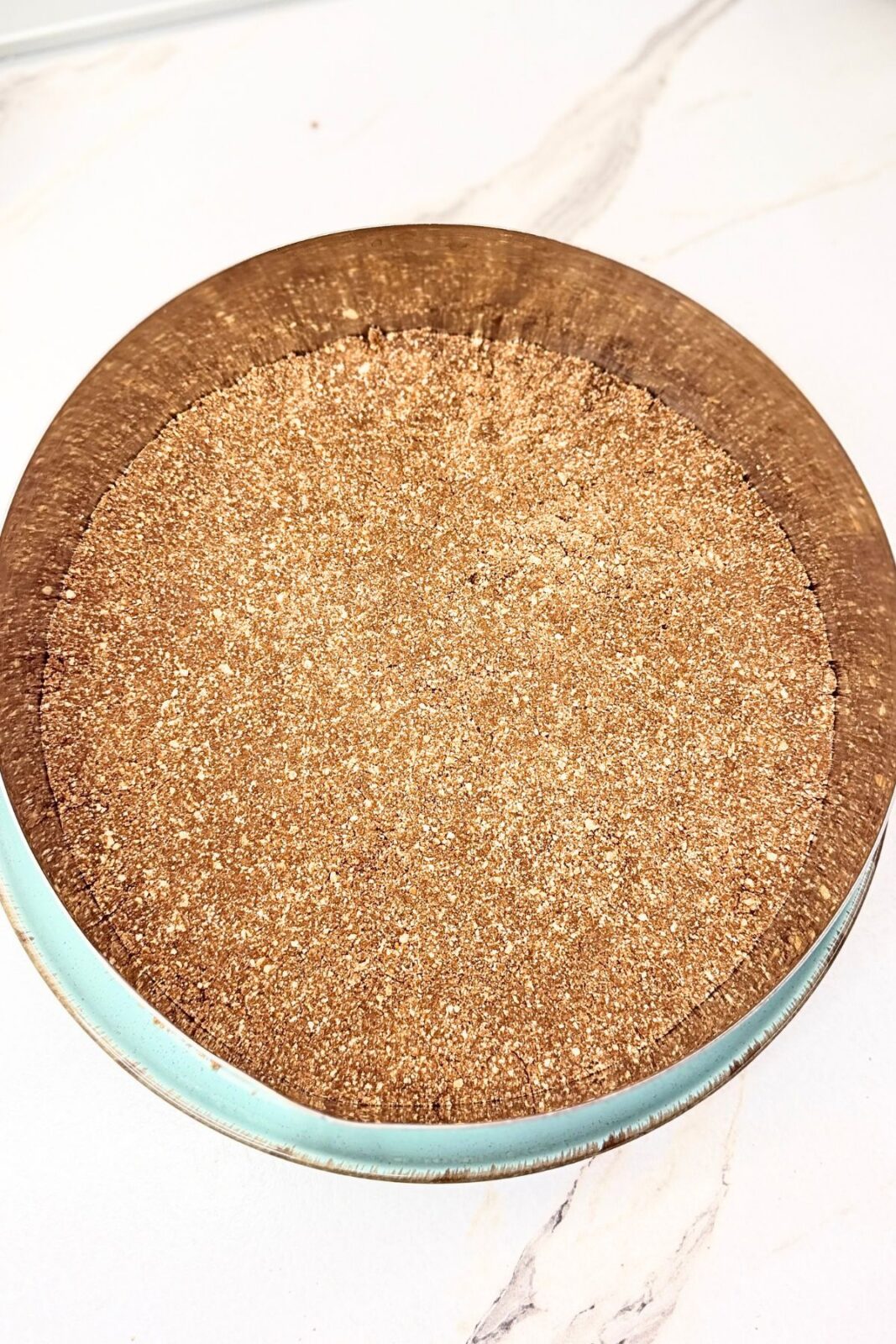 Cocoa cookie crust gently pressed into an even layer inside a round cake ring.
