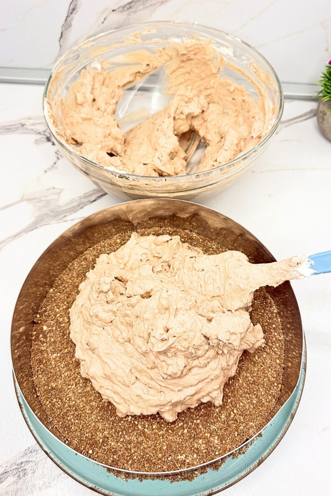 Nutella cream filling being spread over the cocoa cookie crust inside a cake ring.