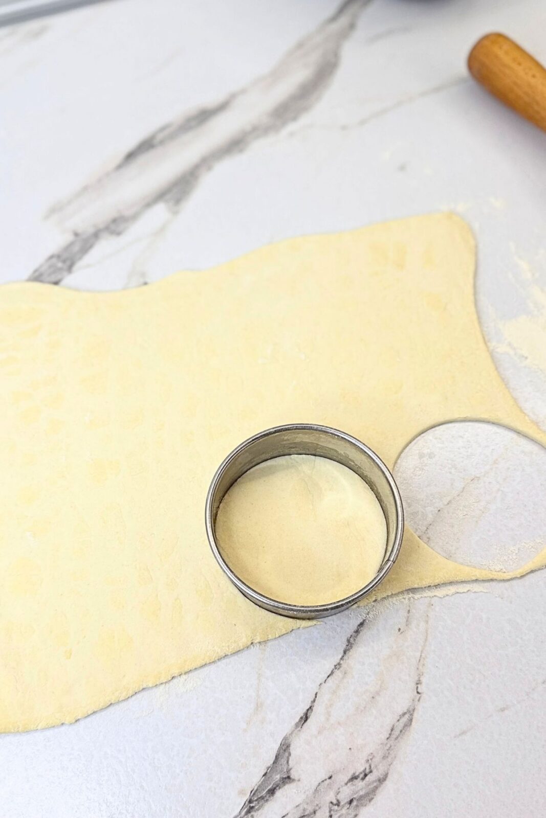 Cutting circles from rolled puff pastry with a round cutter to make puff pastry cups.