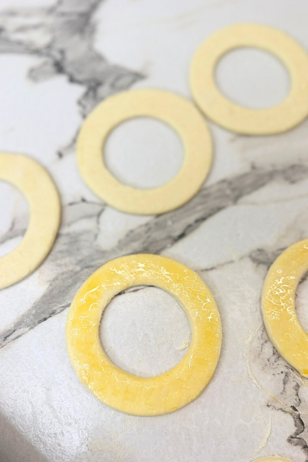 Puff pastry rings brushed with beaten egg before stacking.