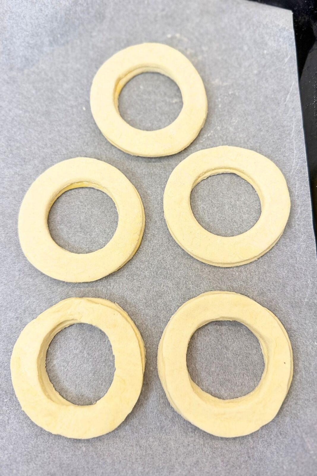 Pairs of stacked puff pastry rings on a parchment-lined baking sheet, ready to bake.