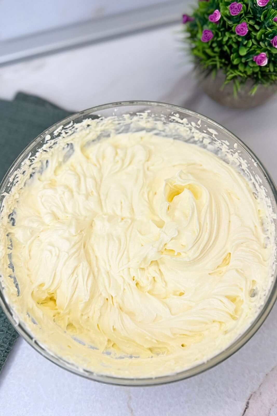 Whipped vanilla cream in a glass mixing bowl, ready to pipe into cooled puff pastry cups.