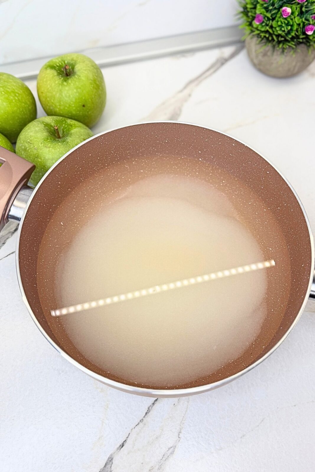 Sugar and water in a saucepan to make the poaching syrup for walnut stuffed apples.