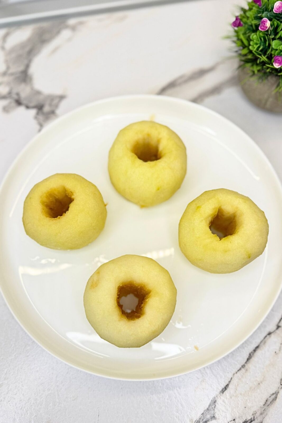 Four poached apples cooling on a white platter before adding the walnut filling.